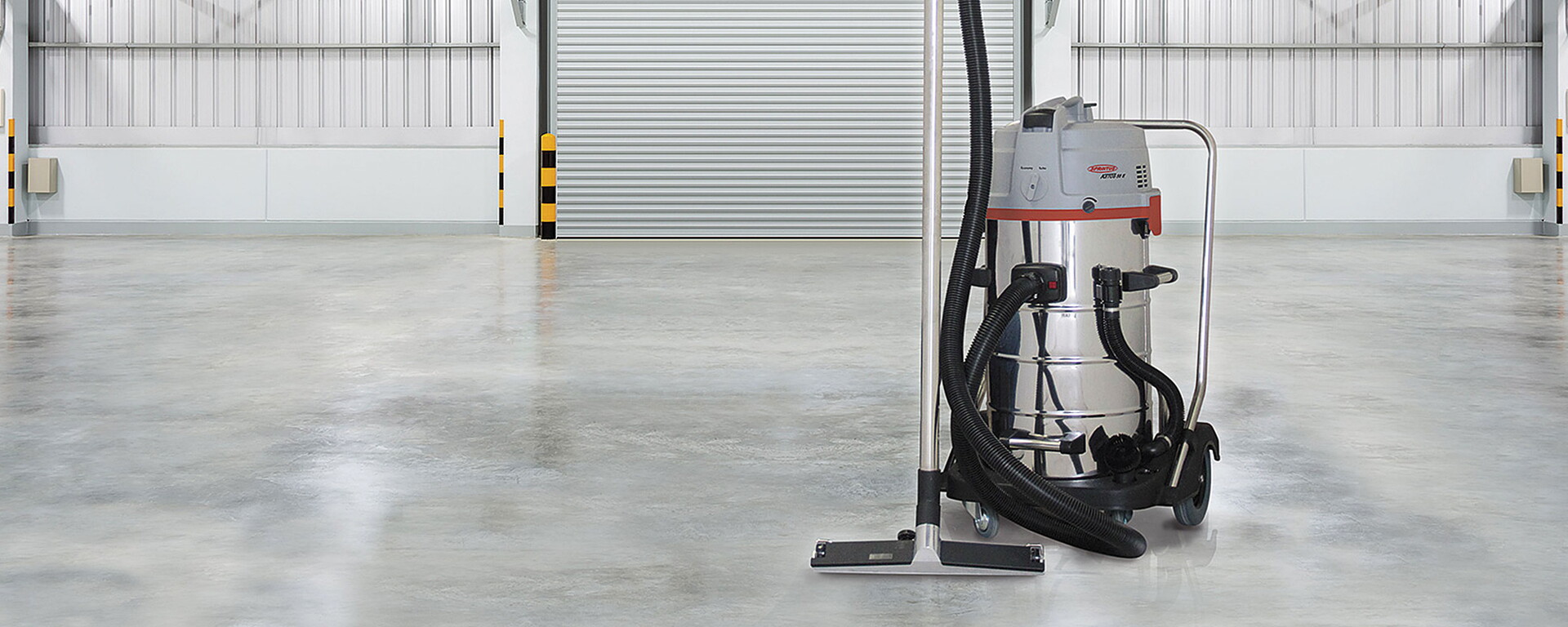 Nass-Trockensauger der Marke Sprintus - silber-grauer Industriesauger in einer Halle mit Rolltor im Hintergrund
